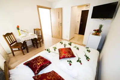 a room with a white table with red pillows on it at Królewski Apartament in Kraków