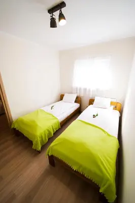 two beds in a room with green sheets at Królewski Apartament in Kraków