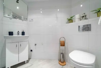 a white bathroom with a toilet and a sink at 2 Nights Apartments - great location, right next to Main Rail and Bus Station, 10 min to Main Square by foot in Kraków