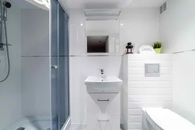 a white bathroom with a sink and a shower at 2 Nights Apartments - great location, right next to Main Rail and Bus Station, 10 min to Main Square by foot in Kraków