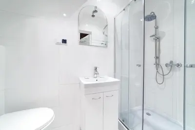 a white bathroom with a sink and a shower at 2 Nights Apartments - great location, right next to Main Rail and Bus Station, 10 min to Main Square by foot in Kraków