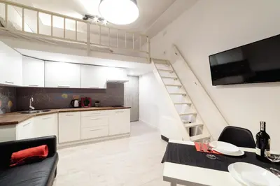 a kitchen and dining room with a staircase in a loft at 2 Nights Apartments - great location, right next to Main Rail and Bus Station, 10 min to Main Square by foot in Kraków