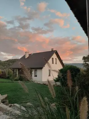 a white house with a sunset in the background at Gospodarstwo Gościnne Księżycówka in Rajbrot
