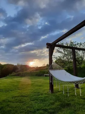 a hammock in a field with the sunset in the background at Gospodarstwo Gościnne Księżycówka in Rajbrot