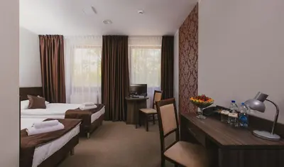 a hotel room with two beds and a desk at Hotel Dąbrowski in Oświęcim