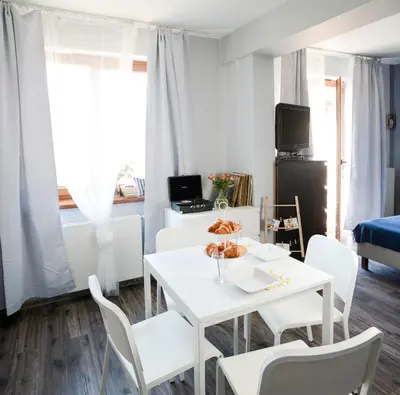 a white dining room with a white table and chairs at Vinyl Apartment Old Town in Kraków
