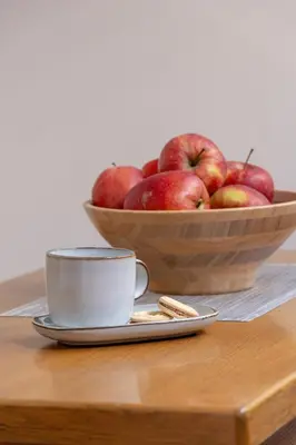 a bowl of apples and a cup on a table at Sunshine apartment in Kraków