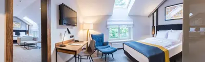 a hotel room with a bed and a desk and a bedroom at Grand Ascot Hotel in Kraków