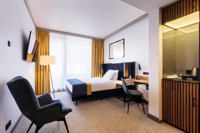 a hotel room with a bed and a desk and chairs at Grand Ascot Hotel in Kraków