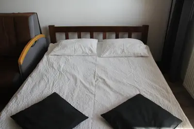 a bed with white sheets and two black pillows at Apartment Wielicka Cracow in Kraków