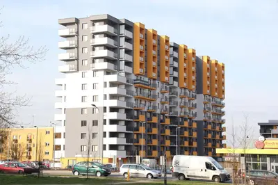 a tall building with cars parked in a parking lot at Apartment Wielicka Cracow in Kraków