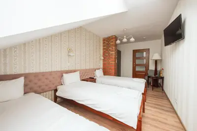 a room with three beds and a television at Ginger ApartHostel in Kraków