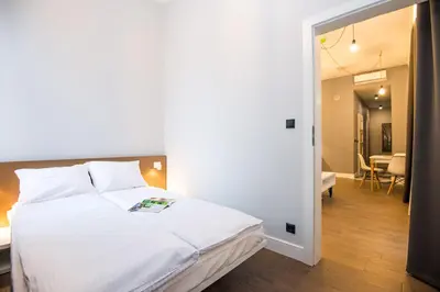 a bedroom with a white bed and a dining room at The Wavelo Collection in Kraków
