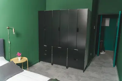 a bedroom with a large black cabinet in a green wall at P&J Apartments Lubicz in Kraków