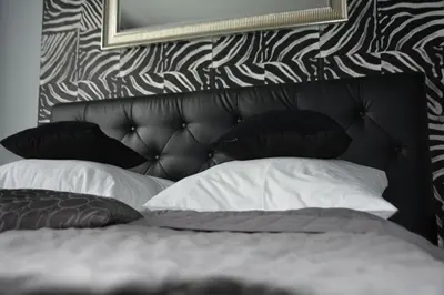 a bed with black and white pillows and a mirror at Angel City MARCO in Kraków
