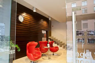 a lobby with red chairs and a table and a clock at Angel City MARCO in Kraków