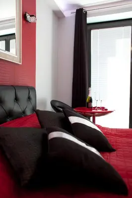 a bed with black pillows and a table with a bottle of wine at Angel City MARCO in Kraków