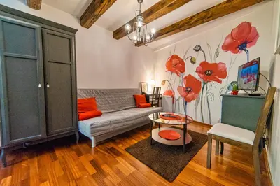 a living room with a couch and red flowers on the wall at Quiet & Cosy Apt in the Heart of Old Cracow in Kraków
