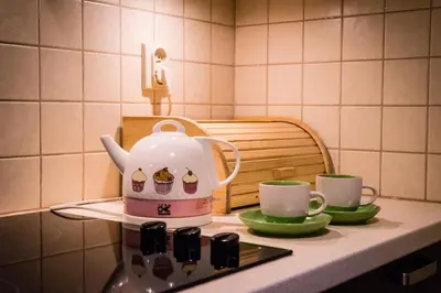 a tea kettle sitting on top of a stove with two cups at Quiet & Cosy Apt in the Heart of Old Cracow in Kraków