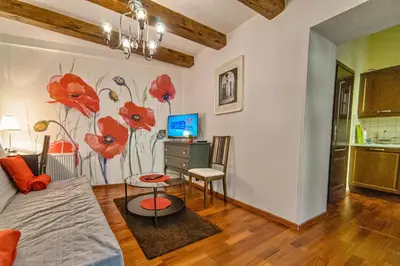 a living room with a painting of red flowers on the wall at Quiet & Cosy Apt in the Heart of Old Cracow in Kraków