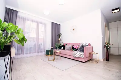 a living room with a pink couch and a table at Apartament Arkadia na Kazimierzu in Kraków