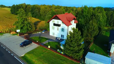 a large white house with a red roof on a street at Agroturystyka Wichrowe Wzgorze in Osiek