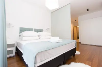 a bedroom with a bed with white sheets and pillows at Lenzo Apartments in Kraków