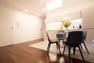 a kitchen with white cabinets and a table and chairs at Lenzo Apartments in Kraków