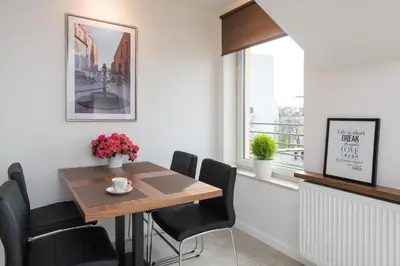 a dining room with a table and chairs and a window at Apartament nad dachami Krakowa in Kraków