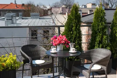 two chairs and a table on a balcony with flowers at Apartament nad dachami Krakowa in Kraków