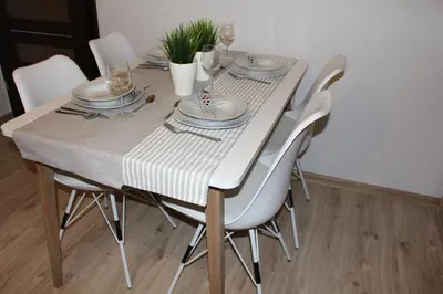 a dining room table with white chairs and plates and glasses at Przy Mocaku II in Kraków