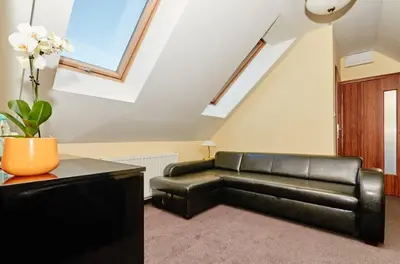 a living room with a black leather couch at Aparthotel W Pałacu in Kraków