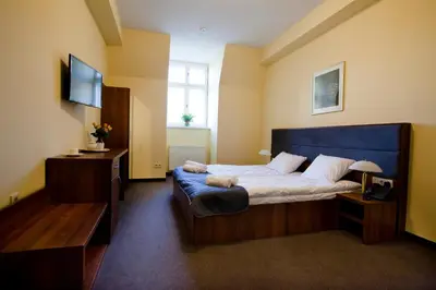 a bedroom with a large bed and a television at Aparthotel W Pałacu in Kraków