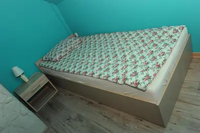 a bed in a room with a blue wall at Domki Oberwanka in Mszana Dolna