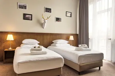 two beds in a hotel room with white sheets at Daniel Griffin Aparthotel by Artery Hotels in Kraków