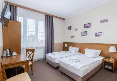 a hotel room with two beds and a desk at Daniel Griffin Aparthotel by Artery Hotels in Kraków