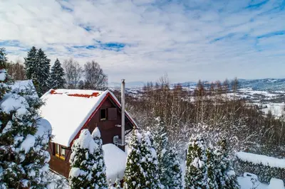 a red cabin with snow on the roof at U Kazika w górach in Ślemień