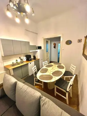 a living room with a table and a kitchen at Pokoje Gościnne Wiślna in Kraków