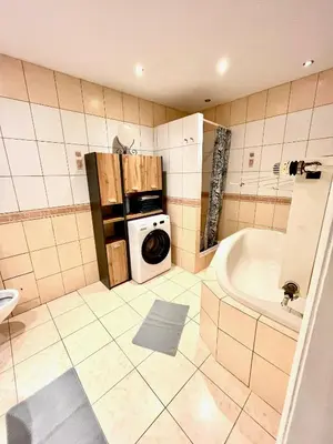 a bathroom with a washing machine and a tub at Pokoje Gościnne Wiślna in Kraków