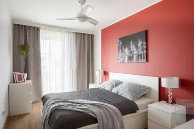a bedroom with a red accent wall and a bed at Jack Apartment in Kraków