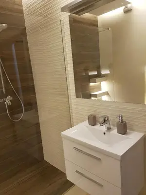 a bathroom with a sink and a mirror and a shower at Jack Apartment in Kraków