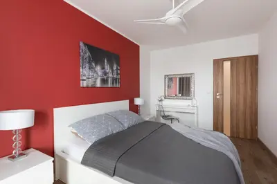 a red bedroom with a bed and a ceiling fan at Jack Apartment in Kraków