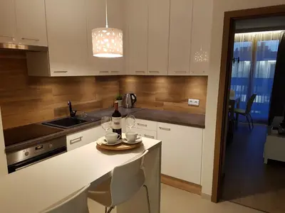 a kitchen with white cabinets and a table with wine glasses at Jack Apartment in Kraków