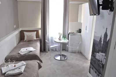 a small room with two beds and a table at Apartamenty Podwale in Kraków
