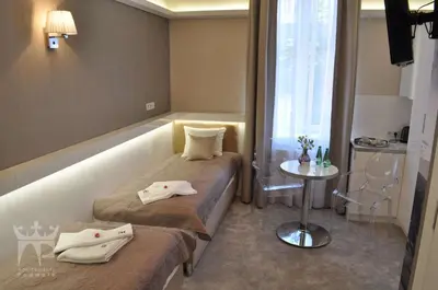 a room with two beds and a table and a window at Apartamenty Podwale in Kraków
