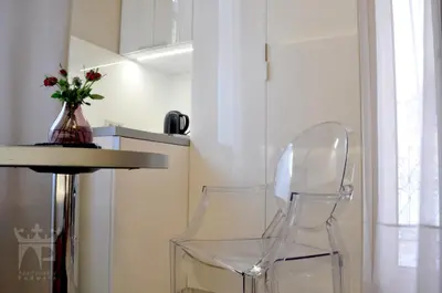 two clear chairs next to a table and a vase with flowers at Apartamenty Podwale in Kraków