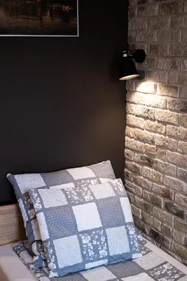 a bed with a quilt on it next to a brick wall at Stawowa Premium Apartment - 69 m2 with sauna and private garage in Kraków