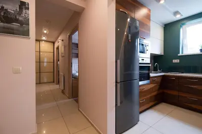 a kitchen with a black refrigerator and wooden cabinets at Stawowa Premium Apartment - 69 m2 with sauna and private garage in Kraków
