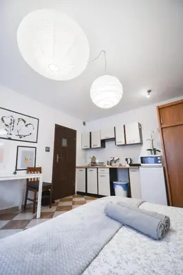 a bedroom with a white bed and a kitchen at LION apartments - Your own apartment in Cracow in Kraków