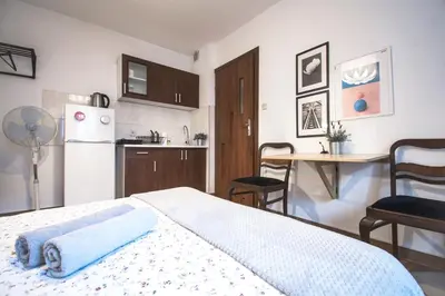 a bedroom with a bed and a kitchen with a refrigerator at LION apartments - Your own apartment in Cracow in Kraków